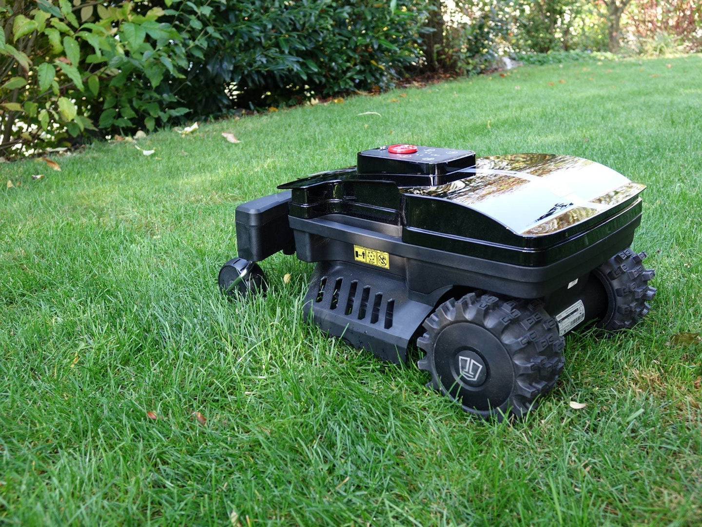 Das Bild zeigt den schwarzen Mähroboter Techline DX25 in einer seitlichen Ansicht, wie er auf einer Wiese steht.