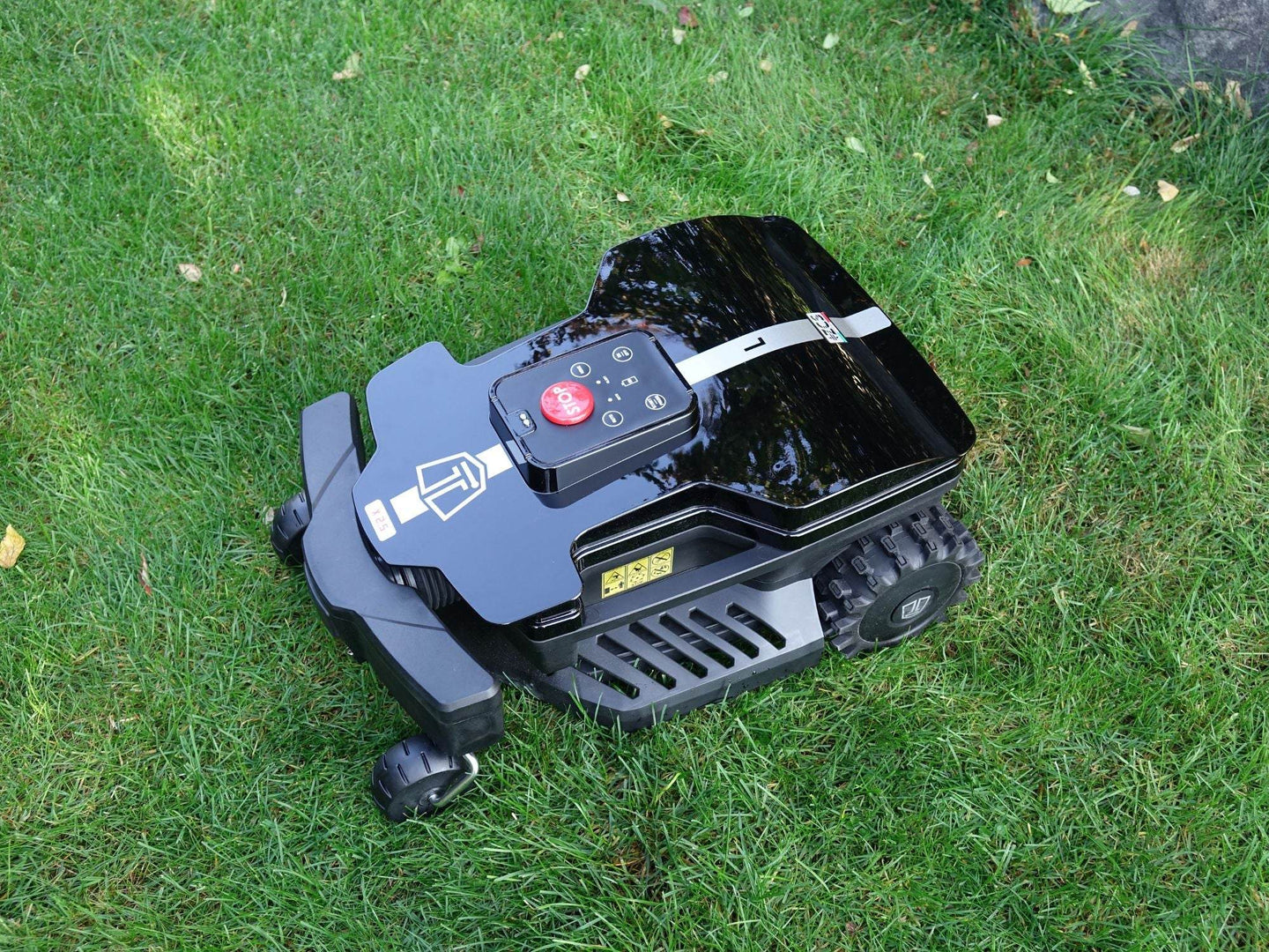 Das Bild zeigt den schwarzen Mähroboter Techline DX25 in einer seitlichen Ansicht von oben, wie er auf einer Wiese steht. Die Aufnahme betont das schlanke und moderne Design des Geräts sowie seine harmonische Integration in die natürliche Umgebung. Die Perspektive von oben bietet einen guten Überblick über die Struktur und die Platzierung des Mähroboters im Garten.