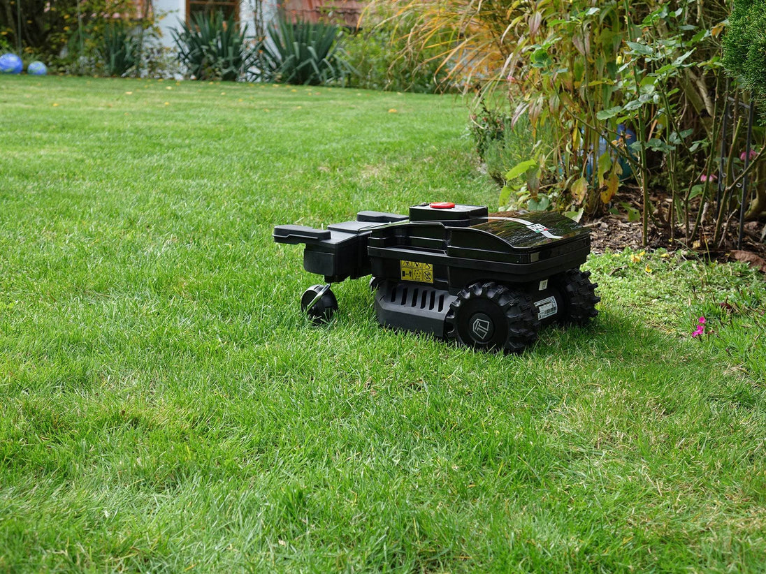 Der schwarze Techline NEXT TECH ZR EVO Mähroboter steht auf einem kurz geschnittenen englischen Rasen. Der Roboter ist von der Seite zu sehen. Er hat oben eine große rote Stopptaste, die den Roboter nach dem Drücken sofort stoppt.